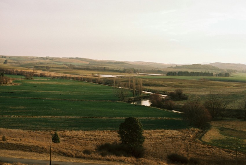 a wide open field with a river running through it