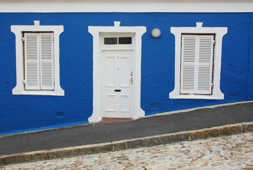 white wooden door on blue concrete wall LE1LfyLpj