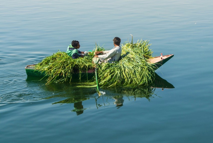 two people on a small boat filled with grass b1KORl