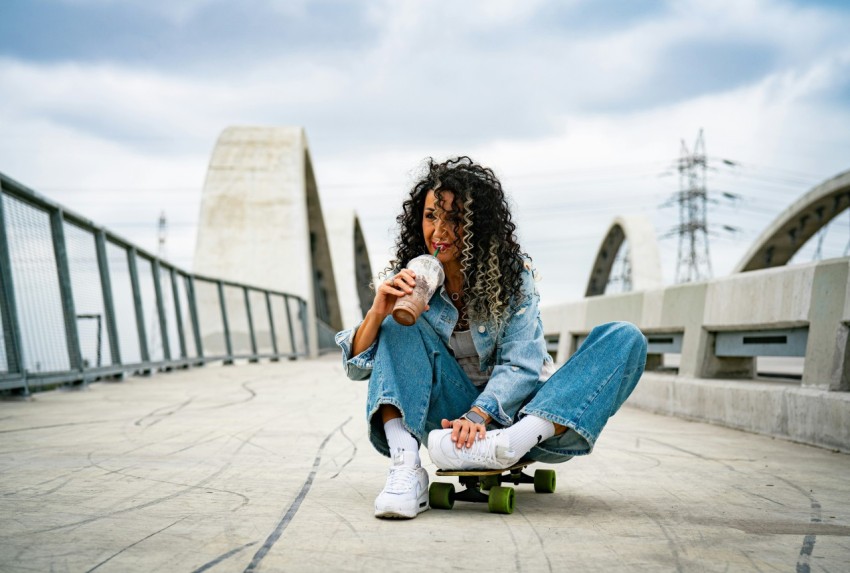 a woman sitting on a skateboard on a bridge