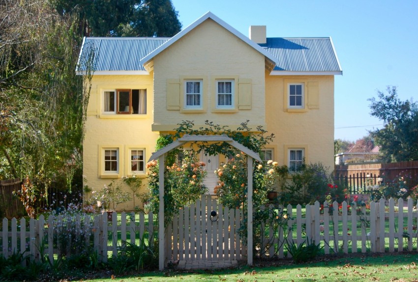 beige concrete house with white wooden fence