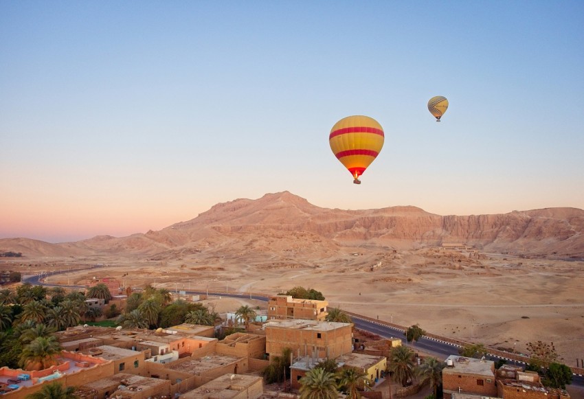 hot air balloon over houses and mountains during daytime