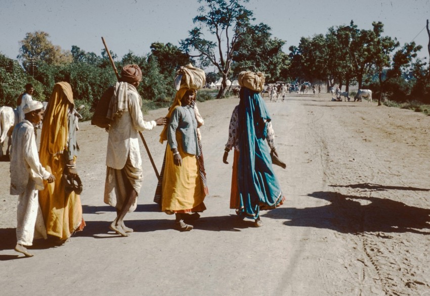 a group of people walking down a dirt road