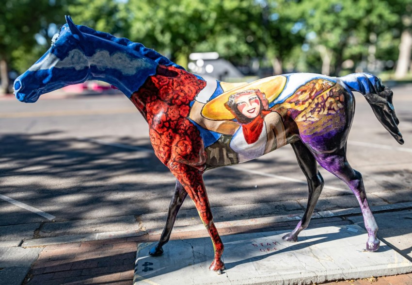 a colorful horse statue on the side of the road