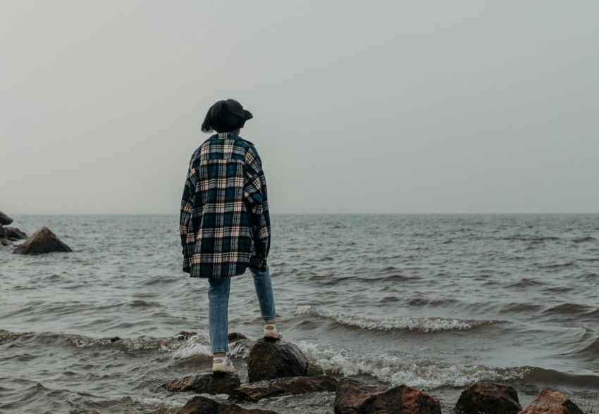 a person standing on rocks near the ocean