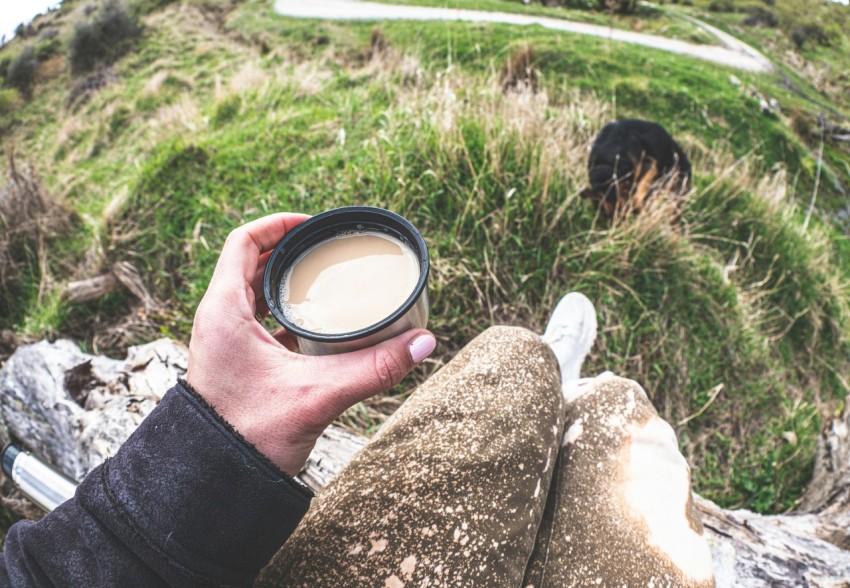 a person holding a cup of coffee on top of a hill