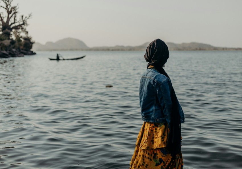 a woman standing in front of a body of water