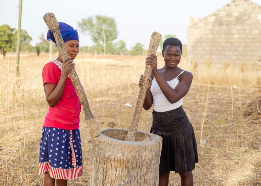 a couple of women holding a wooden pole in a field