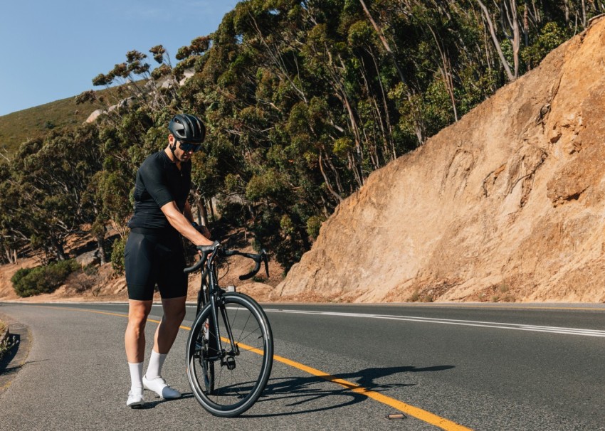 a man standing next to a bike on the side of a road