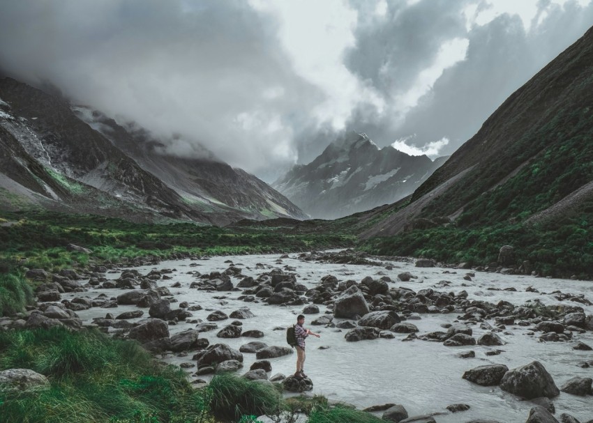 standing person wearing backpack near river