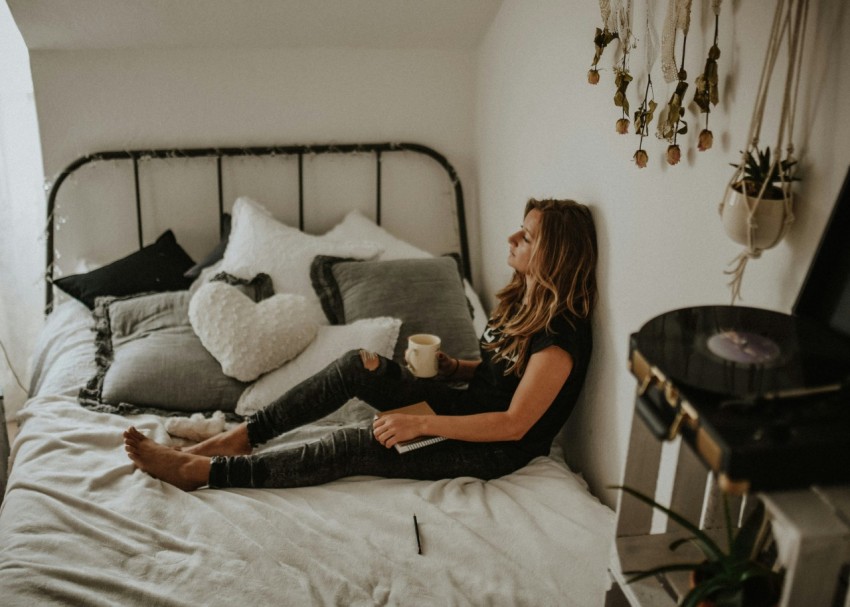 woman leaning on wall while sitting on bed ppWX6_Z1