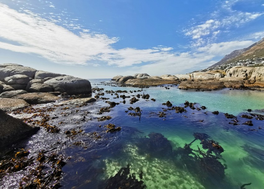 a body of water surrounded by rocks under a blue sky