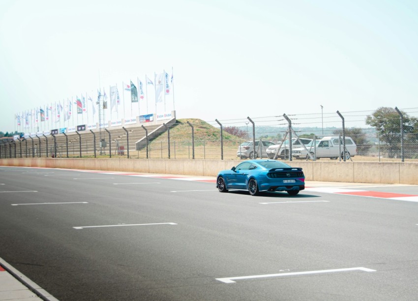 a blue car on a road with flags on the side