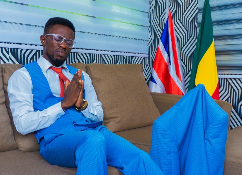 man in blue dress shirt and blue pants sitting on brown couch