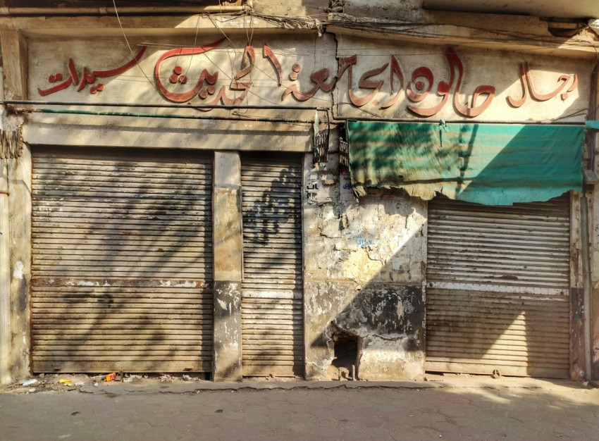 a run down building with closed shutters and graffiti on it