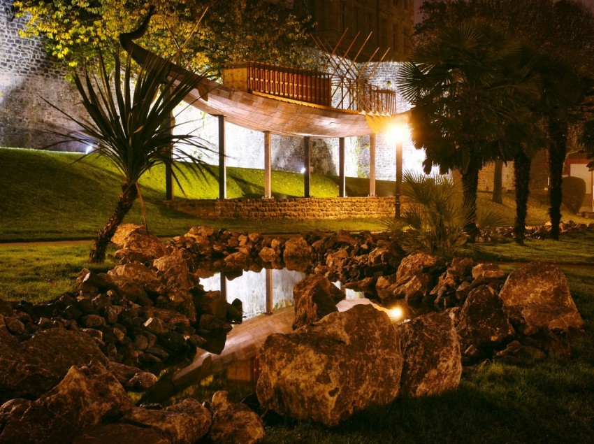 a pond surrounded by rocks and trees at night