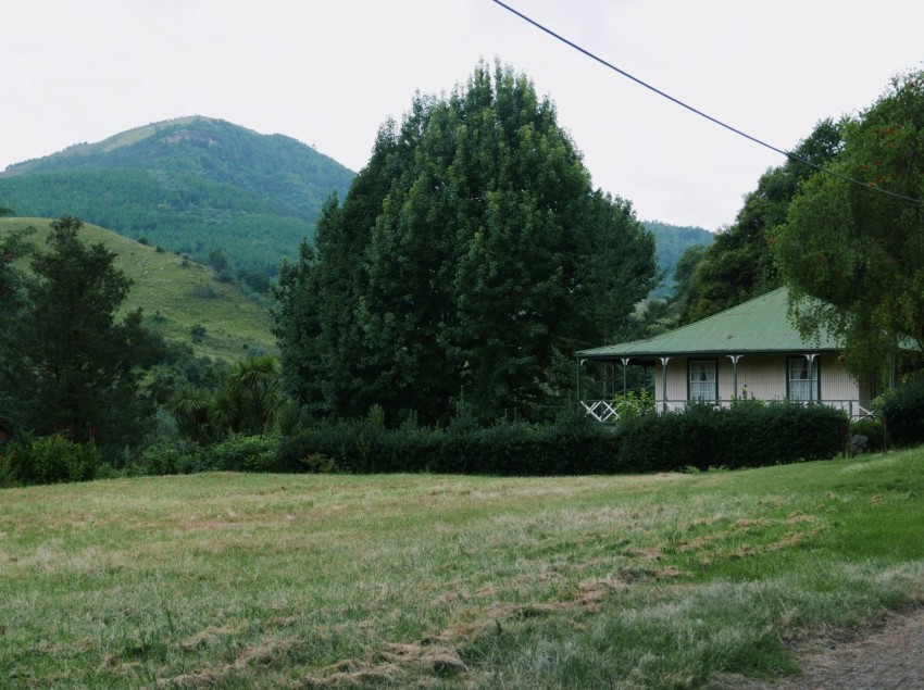 a house in the middle of a field with mountains in the background