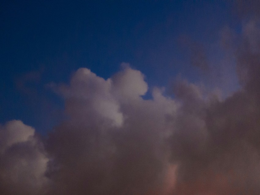 a plane flying through a cloudy blue sky