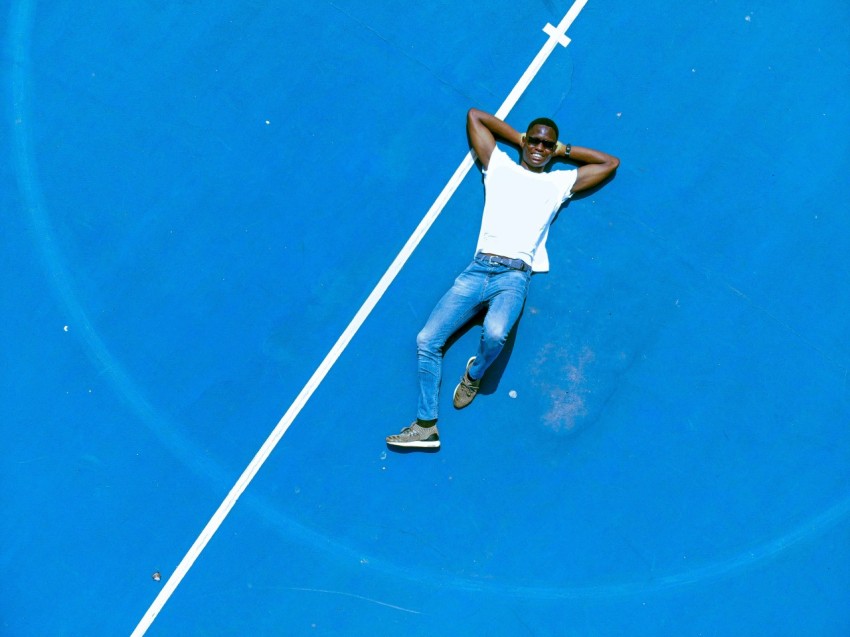 man in white tank top and blue denim jeans riding on white and black kick scooter