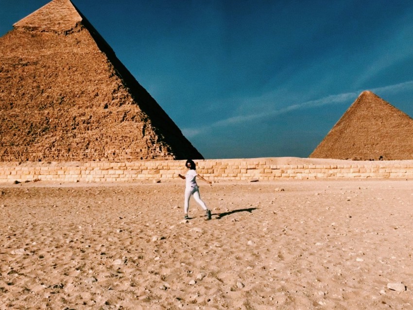 man in white shirt and gray pants walking on brown sand during daytime n