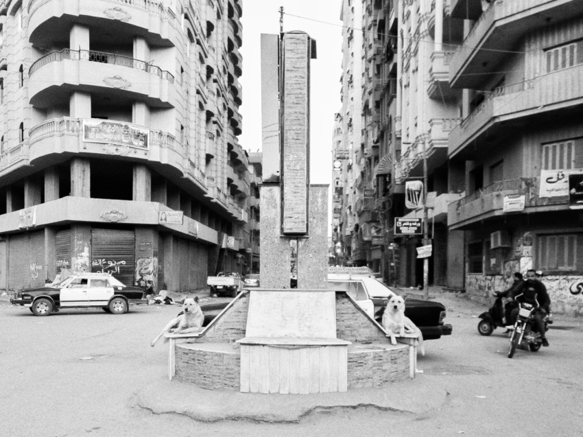 grayscale photo of people walking on street near high rise building