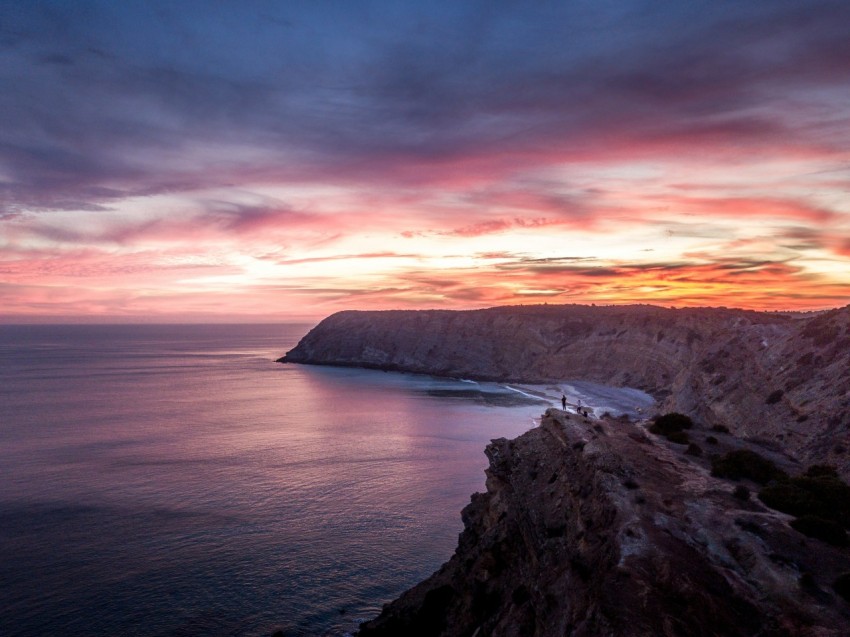 a view of the ocean at sunset from a cliff