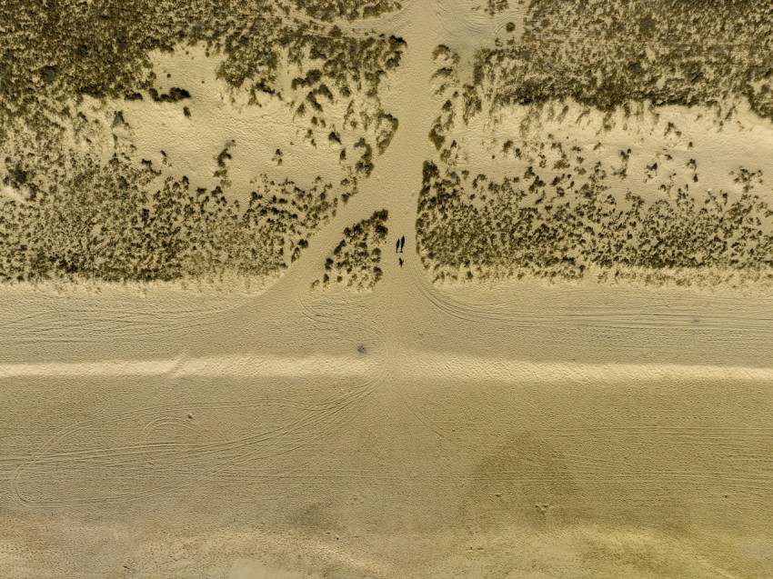 an aerial view of a sandy beach with footprints in the sand