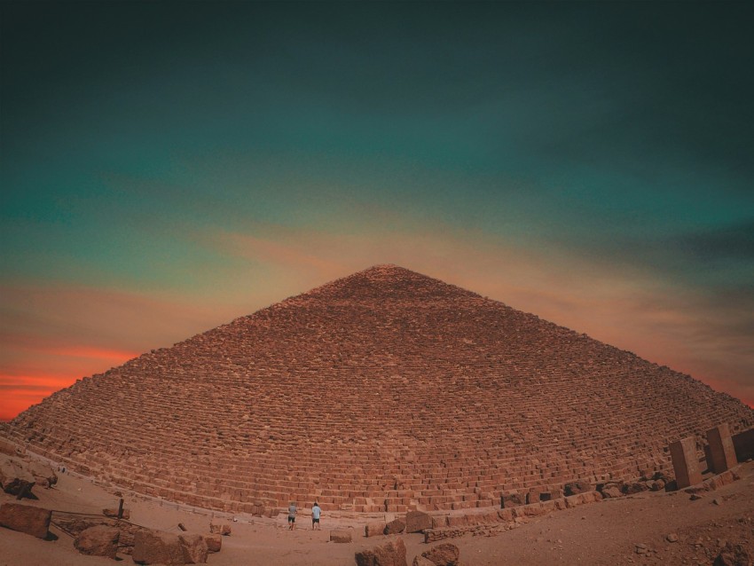 two people standing in front of a large pyramid