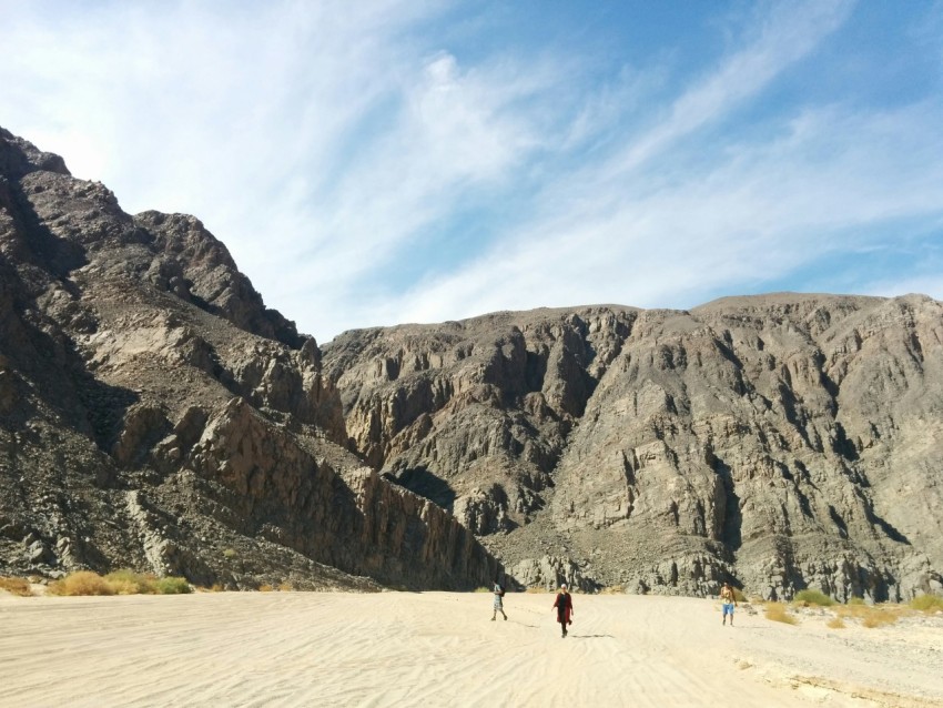 a group of people walking across a sandy field