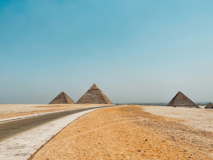 three pyramids in the desert near a road