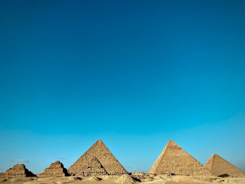 a group of pyramids in the desert under a blue sky