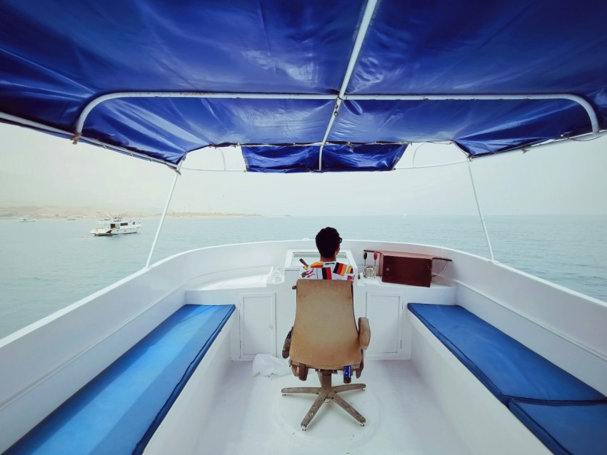 person sitting on chair in boat on body of water