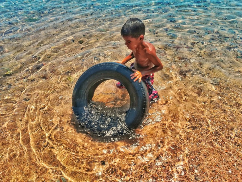 a boy playing with a tire in the water