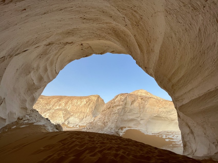 a view from inside of a cave in the desert