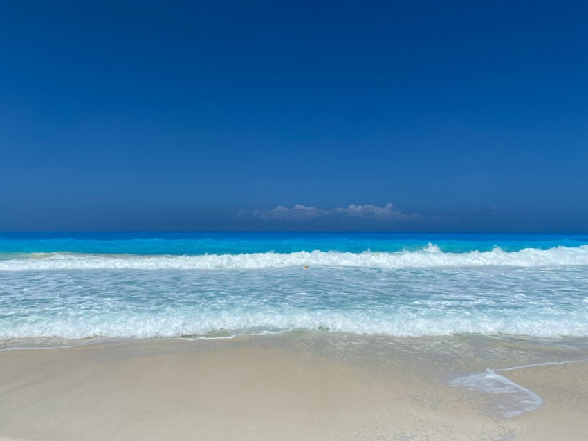 a beach with waves and a blue sky