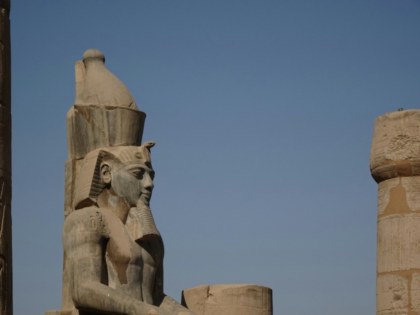 a statue of an egyptian god next to a pillar