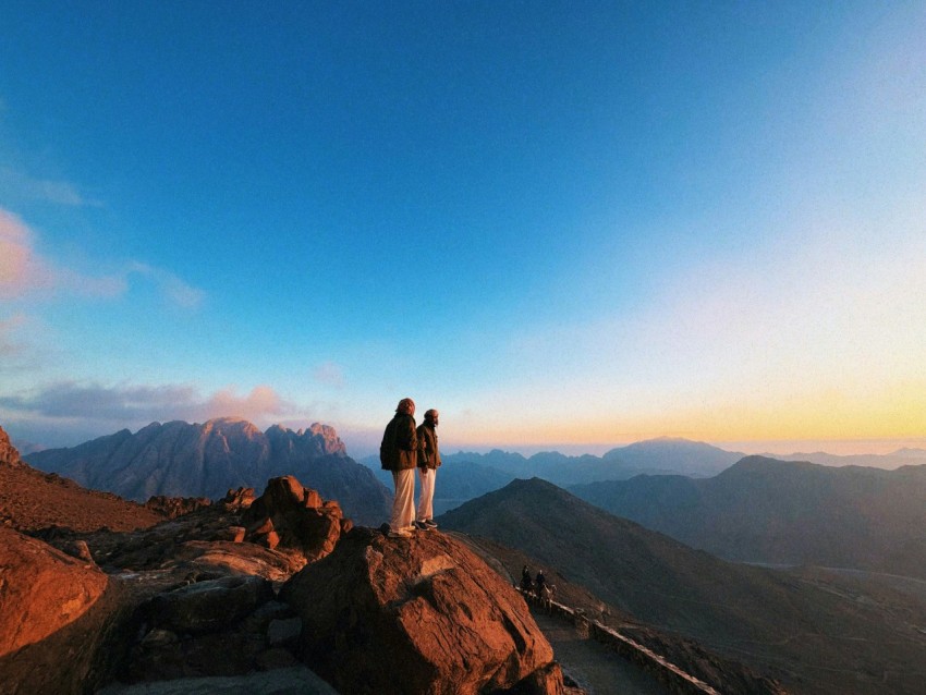 a couple of people standing on top of a mountain