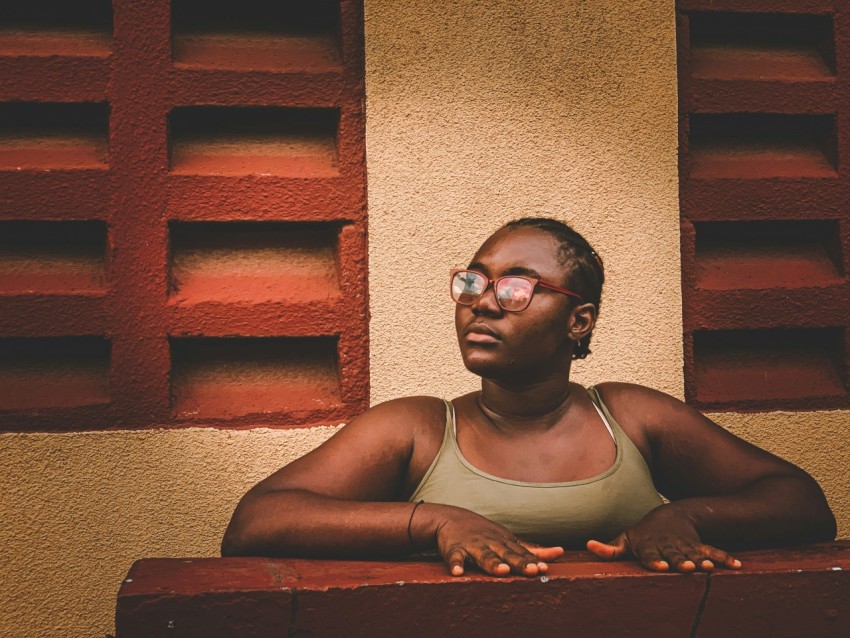 a woman in a tank top sitting on a ledge