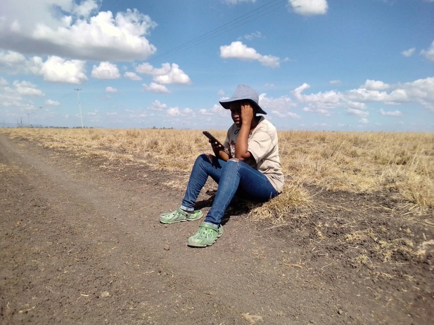 a woman sitting on the side of a dirt road