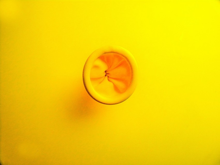 a glass of orange juice on a yellow surface m