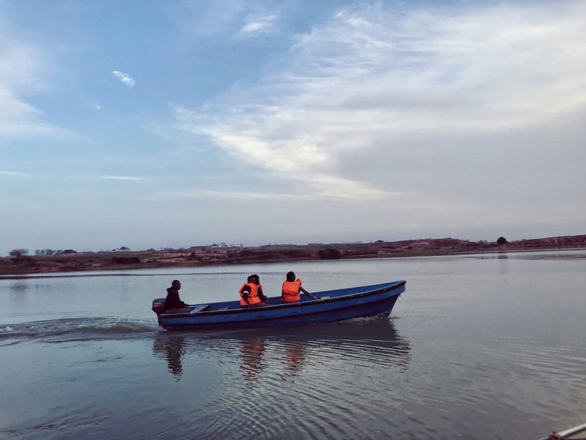 people riding on red and black boat on sea under white clouds and blue sky during