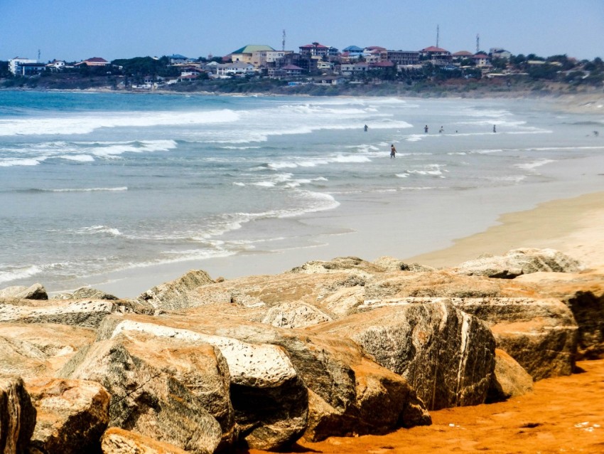 brown rocky shore with people on the beach during daytime Sy0o