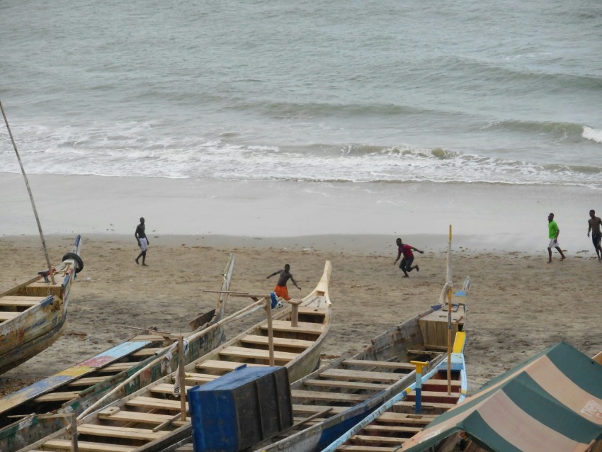 a group of people walking along a beach next to boats r23