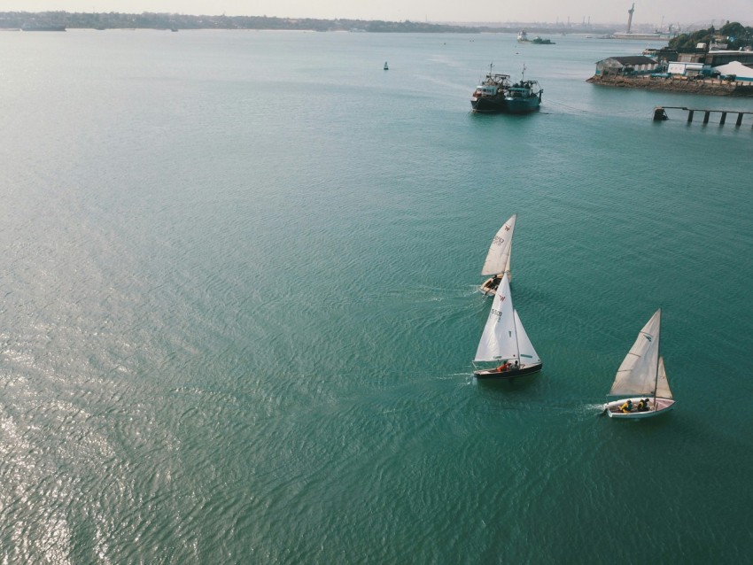 three white sailboats on body of water during daytime 4B6lhgnH