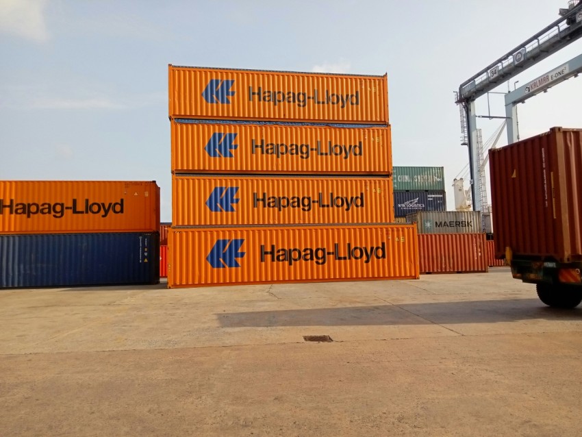 a truck is parked next to a large stack of shipping containers