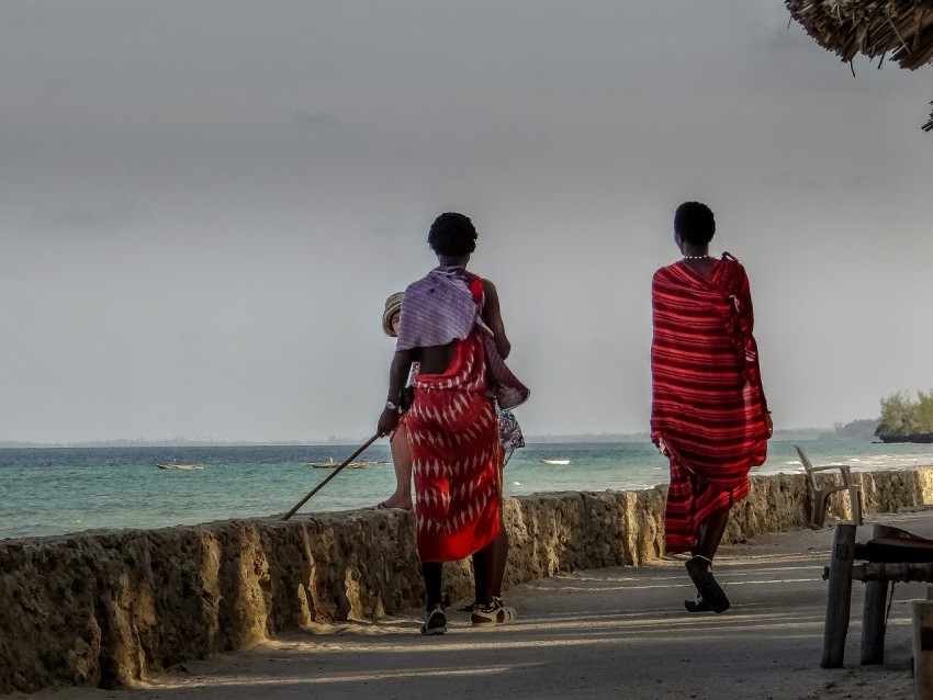 a couple of women walking down a street next to the ocean