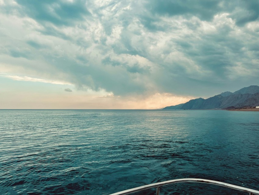 a boat traveling across a large body of water under a cloudy sky