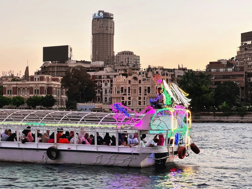 a boat full of people on a river with buildings in the background