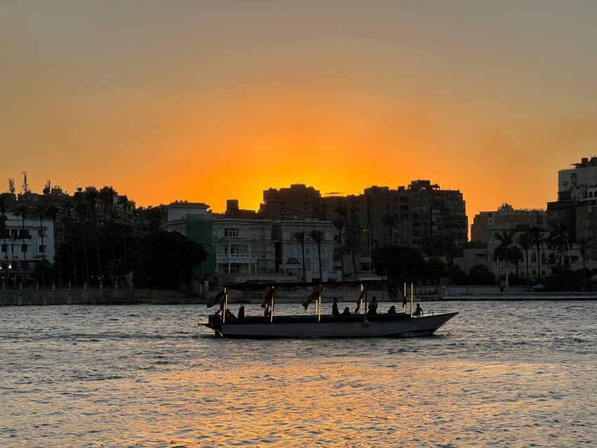 a boat in a body of water with a city in the background bpoM0Uk