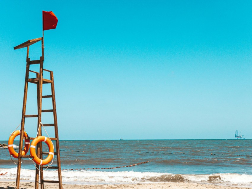 red flag on brown wooden ladder on beach during daytime NM Tj28